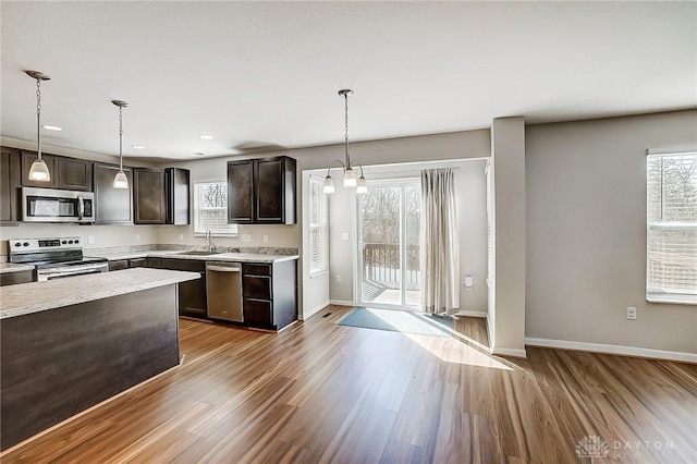 kitchen with plenty of natural light, wood finished floors, dark brown cabinetry, appliances with stainless steel finishes, and light countertops