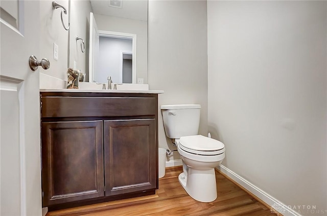 bathroom with toilet, vanity, baseboards, and wood finished floors