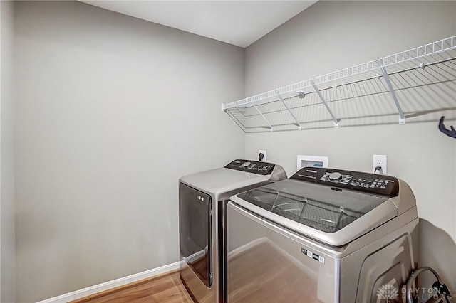 laundry room with laundry area, washer and dryer, baseboards, and wood finished floors