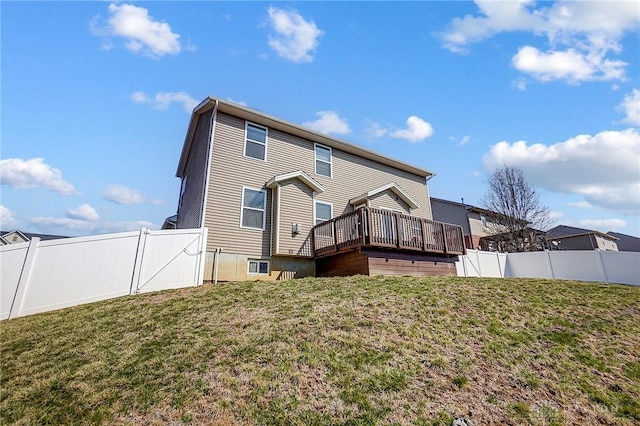 rear view of house with a yard, a wooden deck, and a fenced backyard