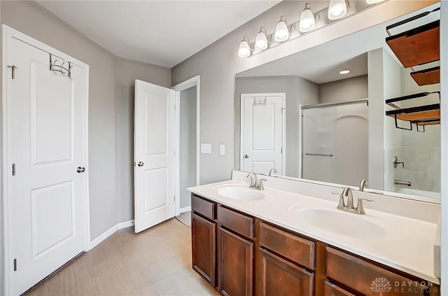 full bathroom with a sink, an enclosed shower, baseboards, and double vanity