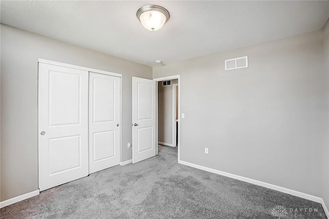 unfurnished bedroom with a closet, visible vents, baseboards, and carpet floors