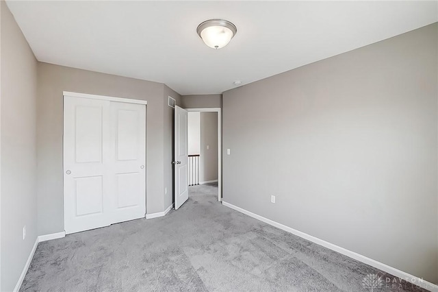 unfurnished bedroom with a closet, visible vents, baseboards, and carpet