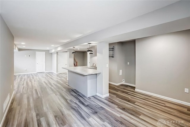 kitchen featuring light wood finished floors, visible vents, baseboards, light countertops, and a sink