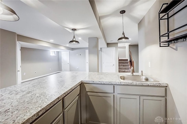 kitchen featuring hanging light fixtures, gray cabinets, light countertops, and a sink