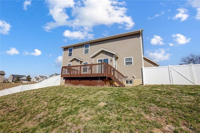 rear view of property featuring a yard, a wooden deck, a fenced backyard, and a gate