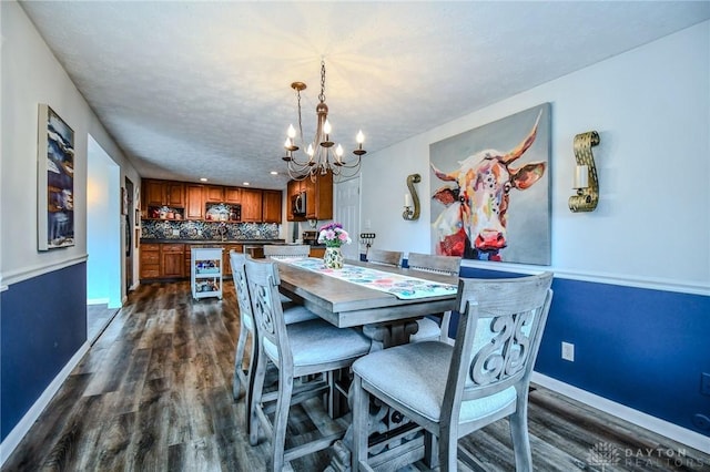 dining space featuring dark wood finished floors, an inviting chandelier, baseboards, and a textured ceiling