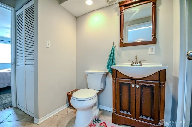 half bathroom featuring vanity, toilet, baseboards, and tile patterned flooring