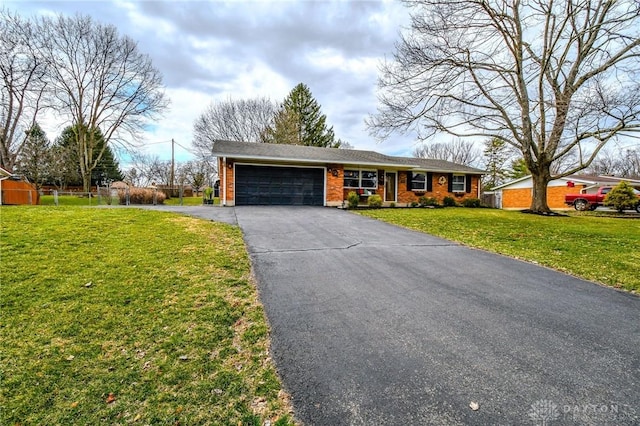 ranch-style house featuring a garage, a front lawn, and driveway