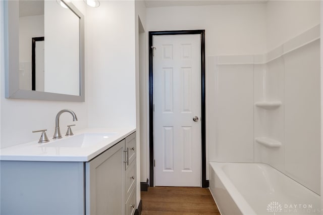 full bath with washtub / shower combination, vanity, and wood finished floors