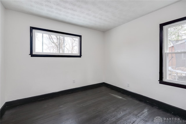 spare room with baseboards, a textured ceiling, and dark wood finished floors