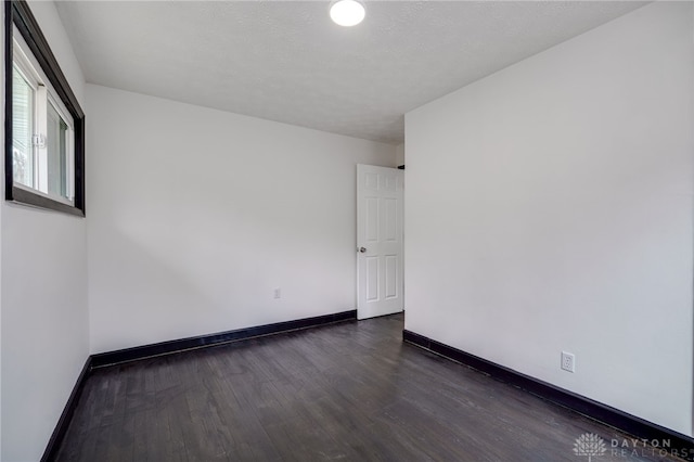 unfurnished room featuring dark wood finished floors, a textured ceiling, and baseboards