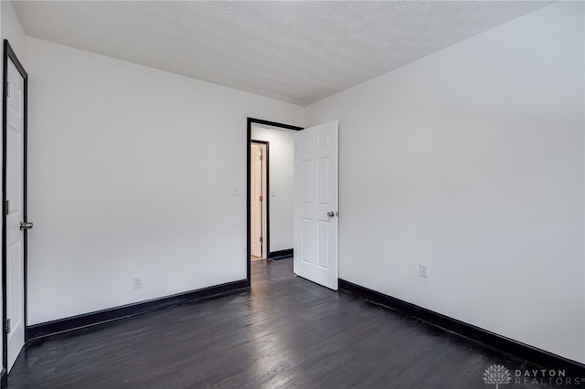 unfurnished room featuring baseboards, a textured ceiling, and dark wood-style flooring