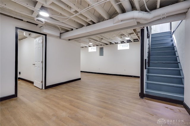 basement with stairway, baseboards, and light wood-type flooring