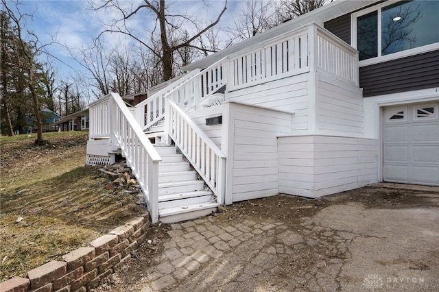 view of side of home featuring stairway, an attached garage, and a deck