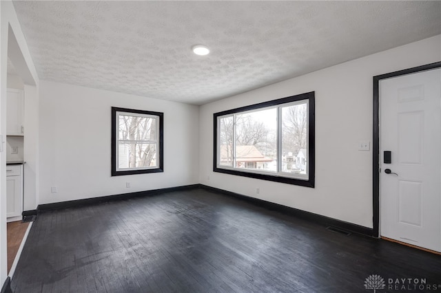 interior space with dark wood-style floors, a textured ceiling, and baseboards