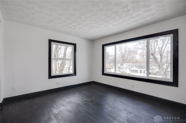 unfurnished room with baseboards, dark wood-style flooring, and a textured ceiling