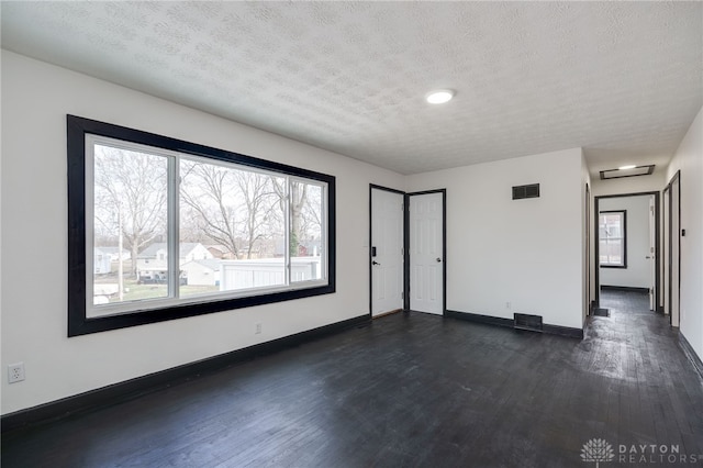 spare room featuring dark wood finished floors, visible vents, and plenty of natural light