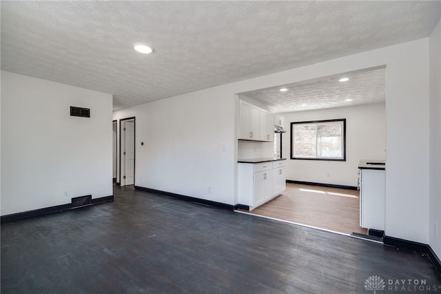 unfurnished living room with visible vents, recessed lighting, dark wood-type flooring, and baseboards