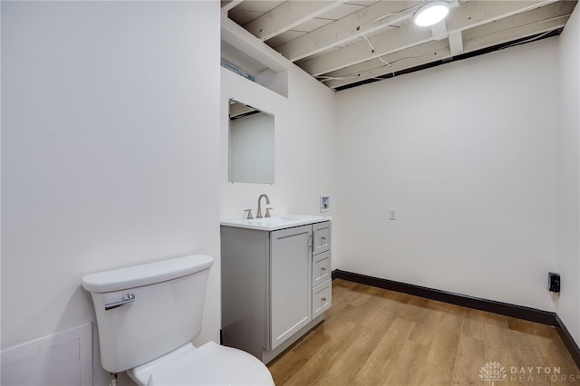 bathroom featuring baseboards, toilet, wood finished floors, and vanity