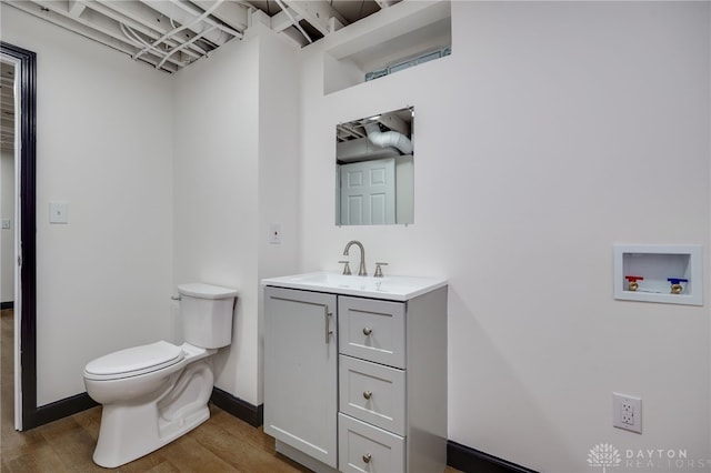 bathroom featuring toilet, vanity, baseboards, and wood finished floors