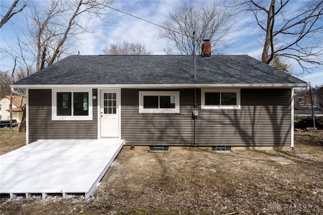 back of house featuring a chimney, a trampoline, and roof with shingles