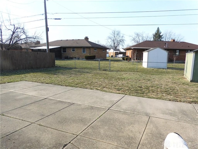 view of yard with a patio area, a storage unit, fence, and an outbuilding