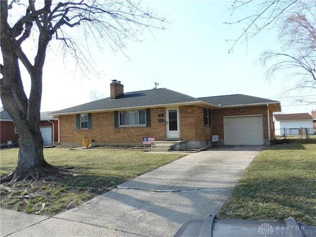 ranch-style house featuring driveway, an attached garage, a chimney, a front lawn, and brick siding