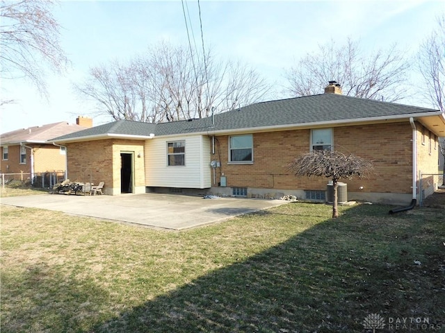 rear view of property featuring a patio area, a chimney, a yard, and brick siding