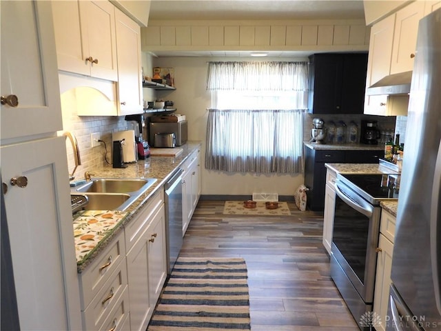 kitchen with tasteful backsplash, visible vents, under cabinet range hood, stainless steel appliances, and a sink