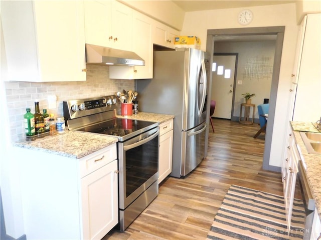 kitchen with decorative backsplash, range hood, light wood-style flooring, stainless steel appliances, and white cabinetry