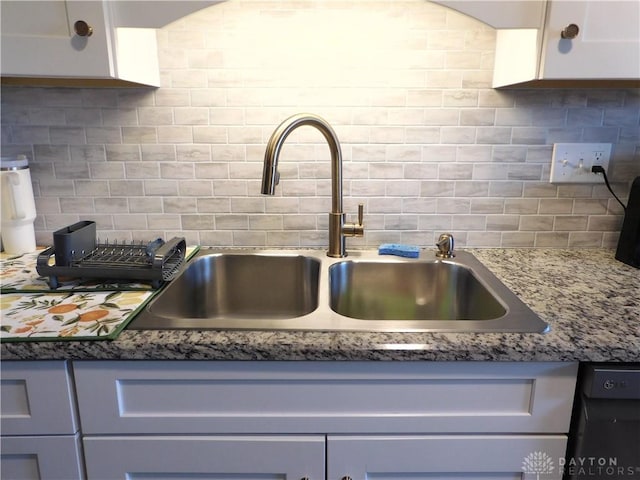 kitchen featuring backsplash, white cabinets, light stone countertops, and a sink