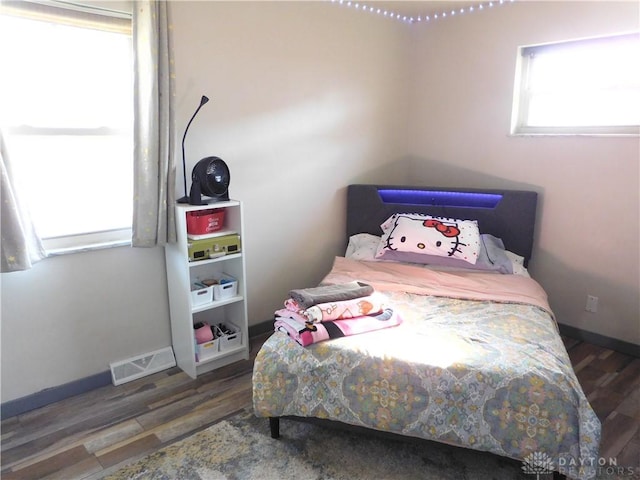 bedroom with visible vents, baseboards, and wood finished floors