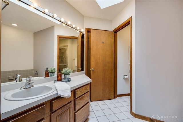 full bath featuring a shower with door, a skylight, vanity, and tile patterned flooring