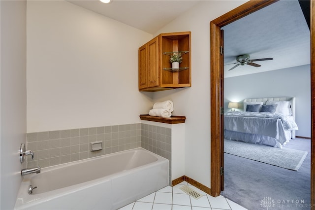 bathroom featuring a ceiling fan, baseboards, ensuite bathroom, tile patterned floors, and a bath