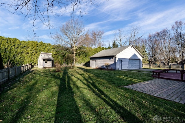 view of yard with a fenced backyard, a patio, a detached garage, and an outdoor structure