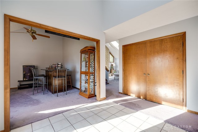 carpeted entryway with tile patterned floors, beam ceiling, high vaulted ceiling, and ceiling fan