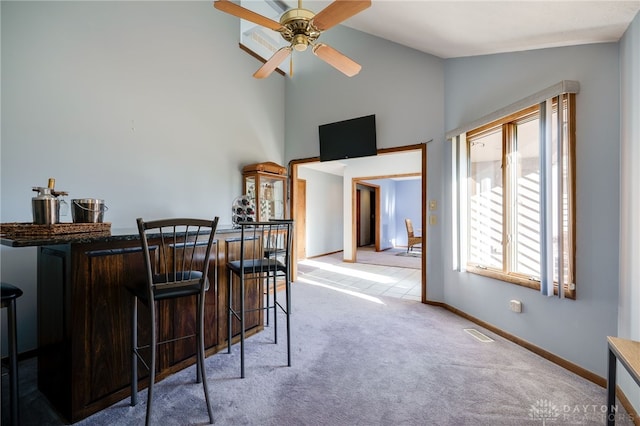 interior space with visible vents, a ceiling fan, carpet floors, baseboards, and a dry bar