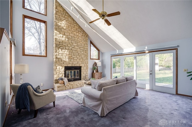 living room with carpet, a stone fireplace, ceiling fan, and high vaulted ceiling