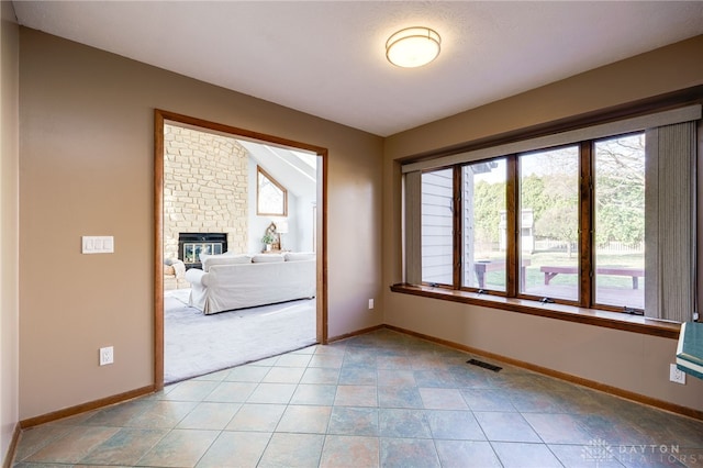 empty room featuring light carpet, visible vents, a fireplace, and baseboards