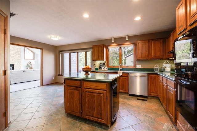 kitchen featuring visible vents, a kitchen island, black appliances, dark countertops, and brown cabinets