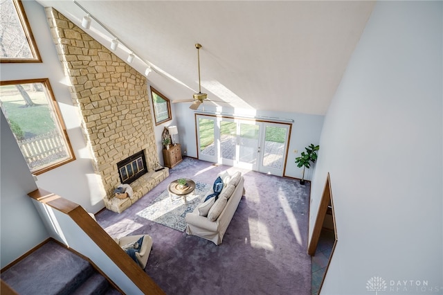 living room featuring high vaulted ceiling, a ceiling fan, carpet floors, rail lighting, and a brick fireplace