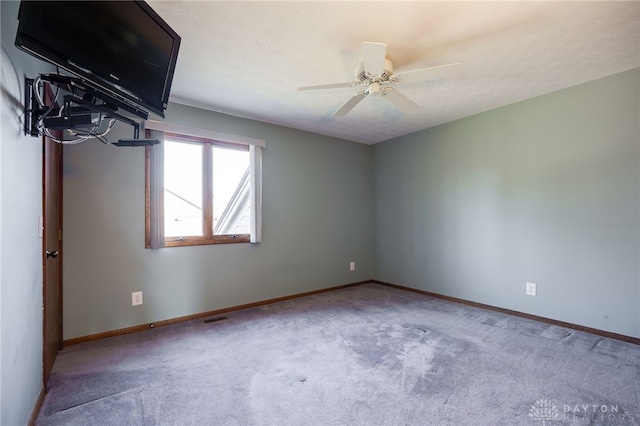 spare room with baseboards, visible vents, carpet floors, ceiling fan, and a textured ceiling