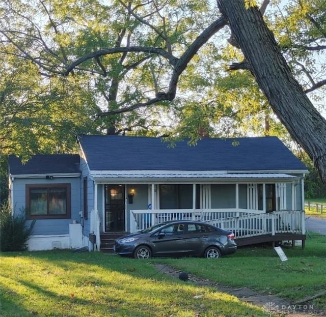 ranch-style home with a porch, a front lawn, and roof with shingles