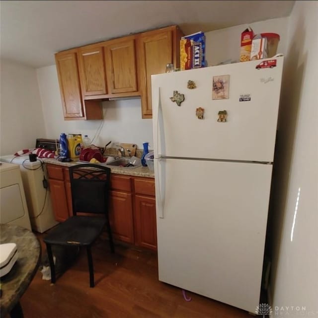 kitchen with separate washer and dryer, dark wood-style flooring, freestanding refrigerator, a sink, and light countertops