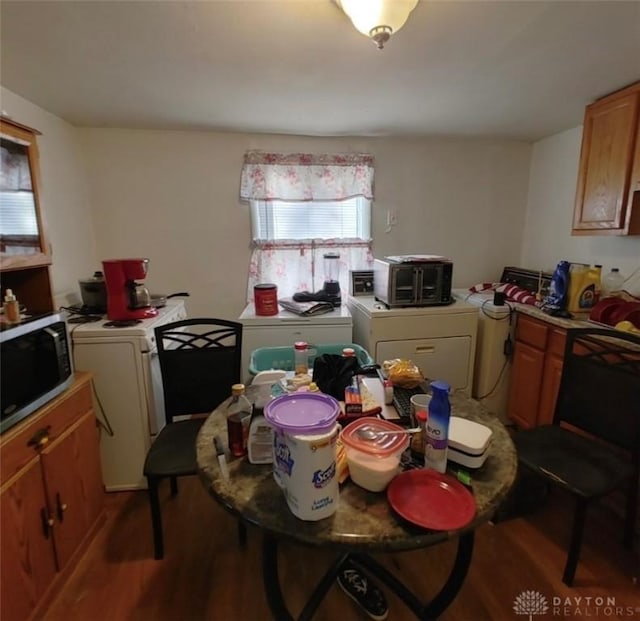 kitchen with washer and dryer, stainless steel microwave, wood finished floors, and light countertops