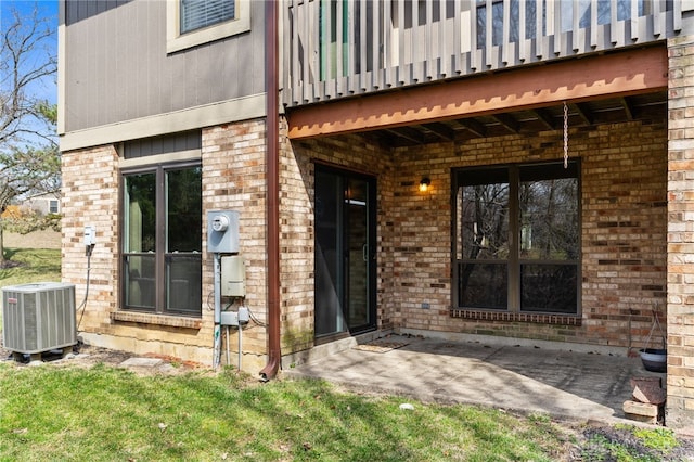 property entrance featuring brick siding, central air condition unit, and a patio area