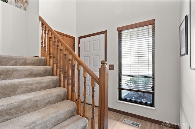 staircase with visible vents, baseboards, and wood finished floors