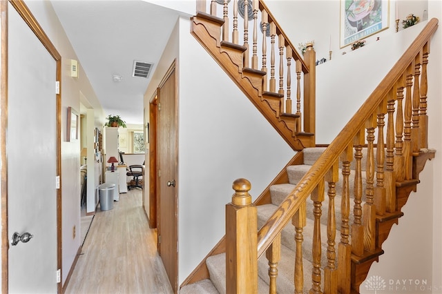 staircase with visible vents and wood finished floors