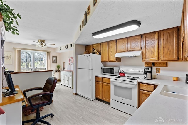 kitchen featuring under cabinet range hood, light countertops, brown cabinetry, white appliances, and a sink